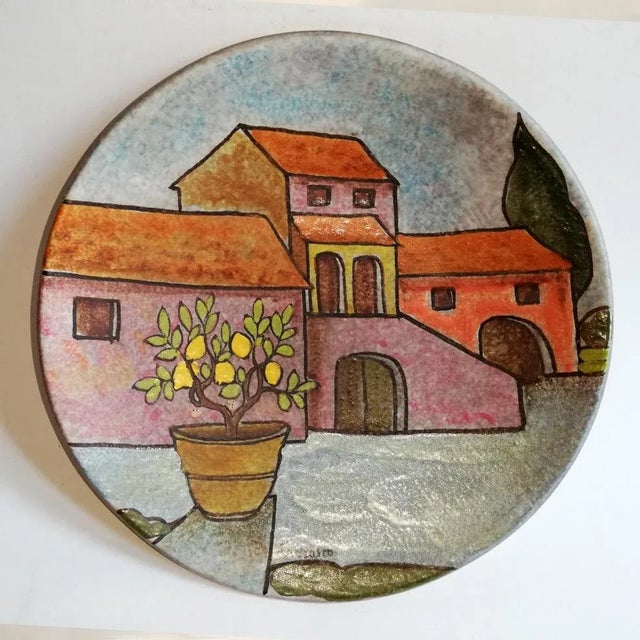 This flat ceramic wall plate depicts a landscape. It retains its Italica ARS label and is signed Lazzaro.