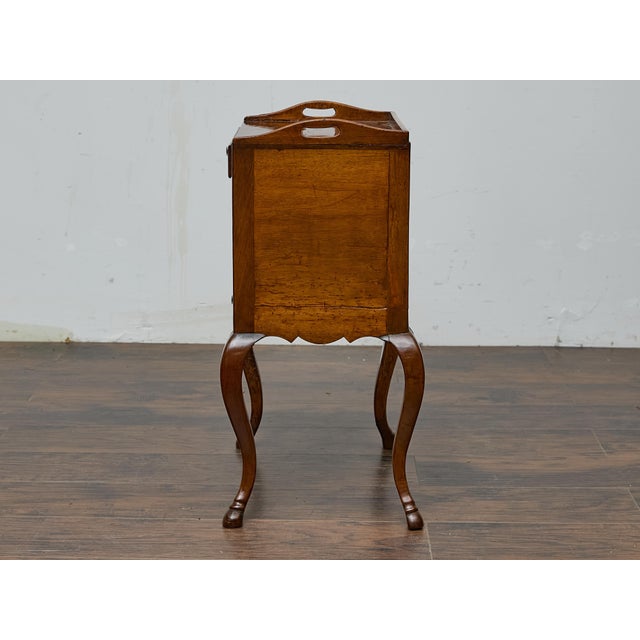 A French 19th-century Louis XV-style walnut bedside table with all the charm of its era. The delicate tray top, complete...