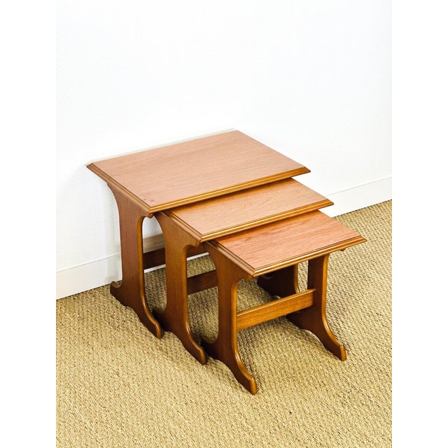 Elegant trio of vintage nesting tables with a design typical of the 1960s. made of teak veneer, they feature a beautiful...