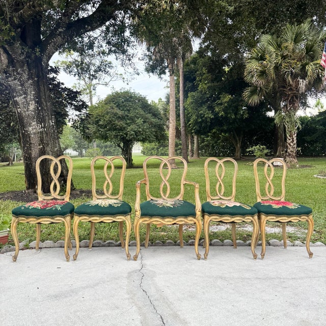 A stunning set of four vintage Rococo-style dining chairs featuring intricately carved wooden frames with graceful...