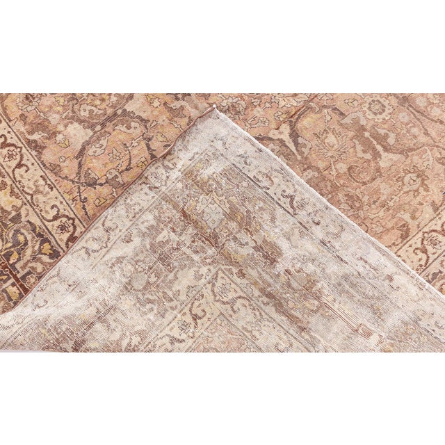 A late 19th century Persian Tabriz carpet, the abrashed camel field with an allover dense trellis design of scrolling...