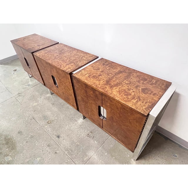 An 8.5 foot long credenza of three cabinets in burl with reflective framework of polished aluminum with inset handles,...