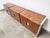 An 8.5 foot long credenza of three cabinets in burl with reflective framework of polished aluminum with inset handles,...