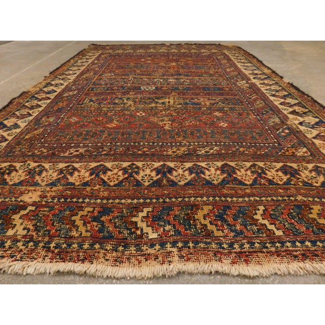 Distressed antique Persian rug. Decorated with motifs throuhout.