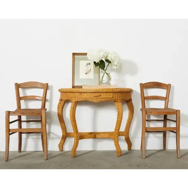 Charming mid-century organic modern demi-lune console table featuring a wood frame covered with fine woven wicker. The...