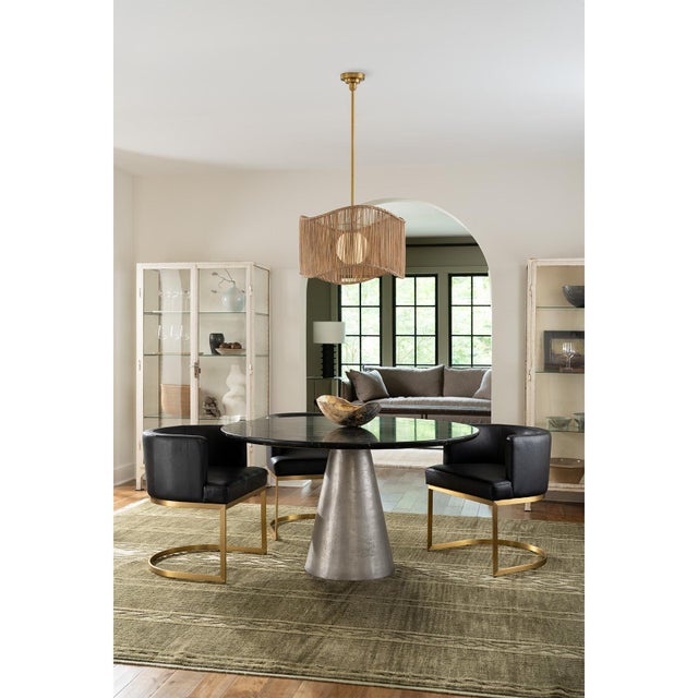 A wide, wavy, woven shade surrounds a white milk glass globe in the Nimes Drum Pendant. Finished in natural brass, the...
