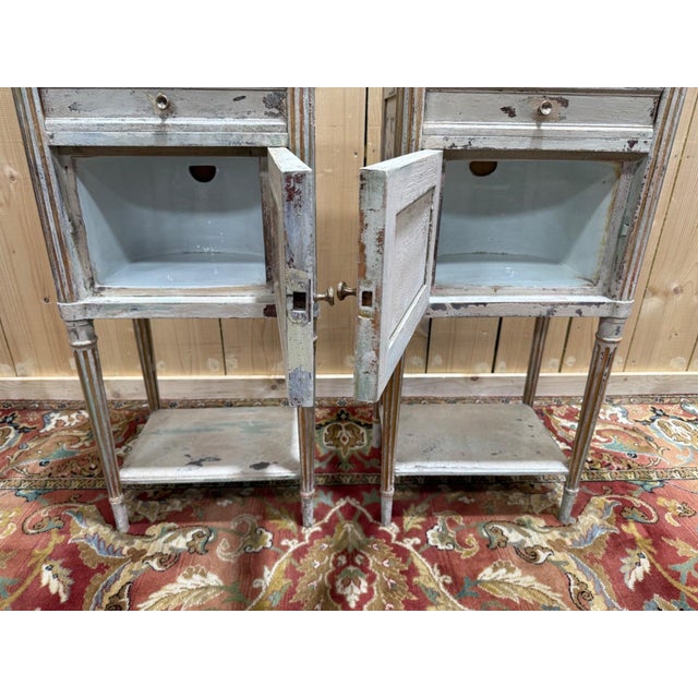 Pair of louis xvi style bedside tables in painted wood with a deliberately aged gray patina revealing several layers of...