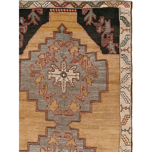 This Mid-20th century Turkish Anatolian room-size carpet presents a bold, vertically ordered composition across a warm...