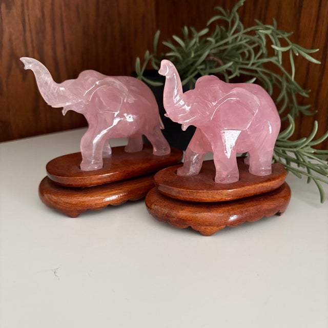 Beautiful pair of vintage hand-carved rose quartz elephants, each mounted on a custom wood base. The soft pink hues and...
