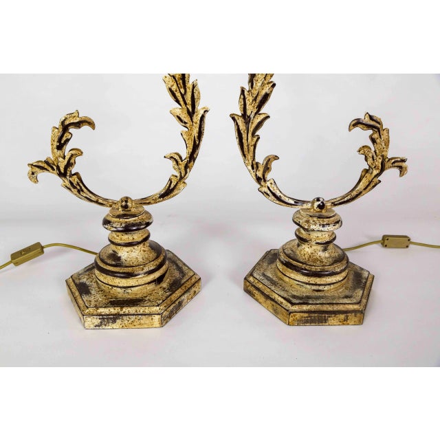 A pair of tole lamps with a unique curved shape. They are slender acanthus leaves with a bloom in the middle mounted on a...