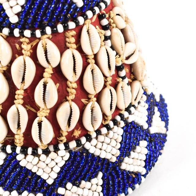 This intricately handwoven hat is covered in glass beads and cowrie shells. The Kuba Beaded Noble's Hat adorned with...