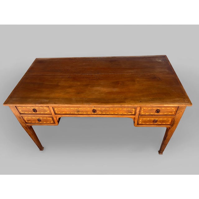 This Louis XVI-style desk is made of walnut with geometric maple and ebony inlays. The piece features five drawers on the...