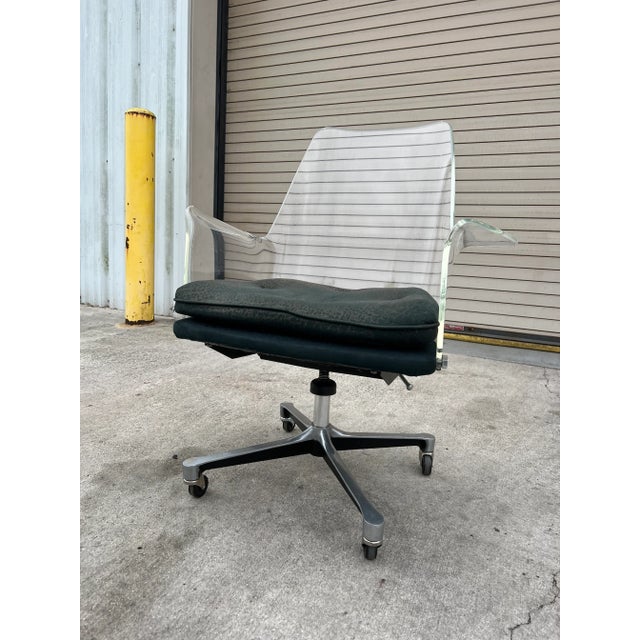 Mid Century circa 1960’s vintage lucite rolling desk chair on an aluminum and black base. Upholstery surface has peeled,...