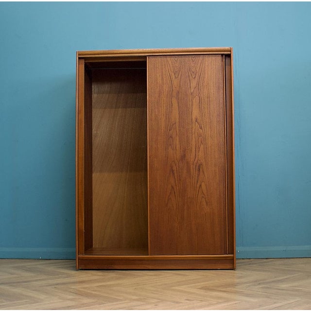 A mid-century Austinsuite wardrobe in teak, with a warm tone and attractive grain across the sliding doors. Clean, simple...