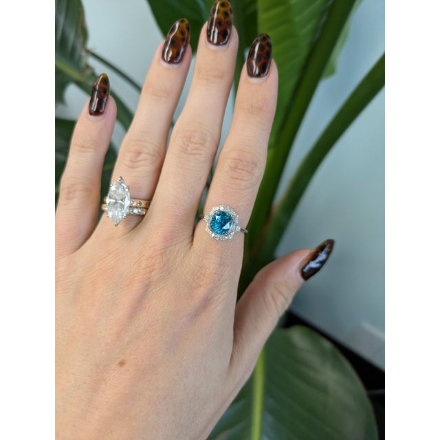 A 4.79-carat cambodian blue zircon cushion sits at the centre of this solid 14K white gold ring, framed by twenty-two...