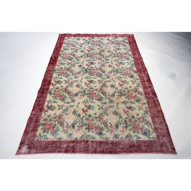 A charming vintage Turkish Isparta rug featuring an elegant all-over rose and floral bouquet design against a warm cream...