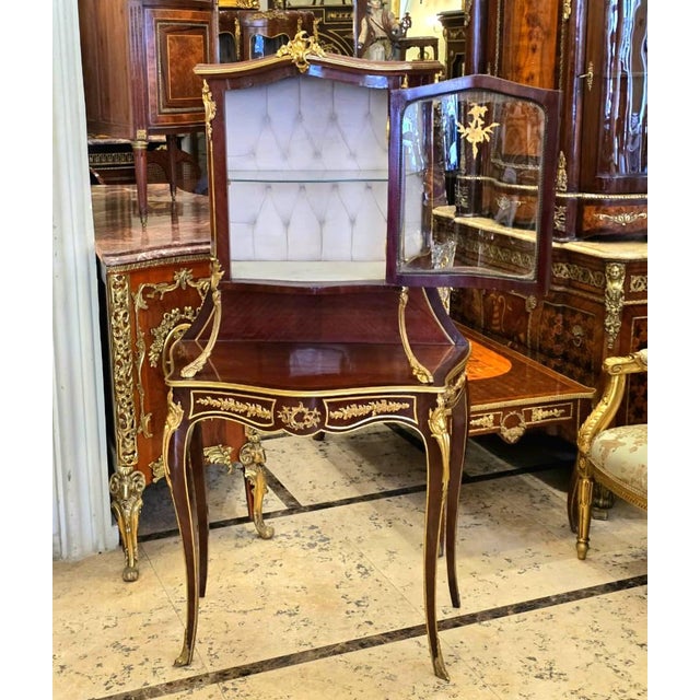An exquisite French Louis XV style display cabinet featuring a beautifully crafted vitrine elevated on an elegant console...