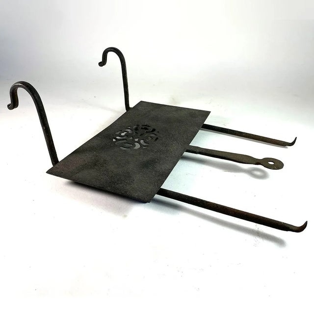 DETAILS An antique fireplace trivet with hooks, a sliding rectangular platform with pierced decoration and a handle. Used...