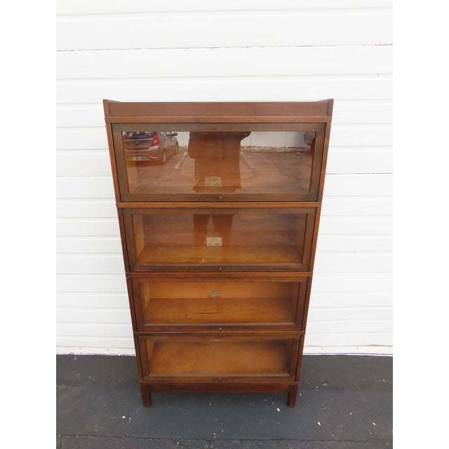 This Lawyer Bookcase is made of wood, solid wood, veneer, and glass. The cabinet is labeled that it was made by Globe...