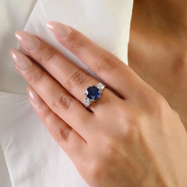 This elegant three-stone ring feature 1 oval cut blue sapphires totaling 2.16 carats set in rich 18k white gold. The...