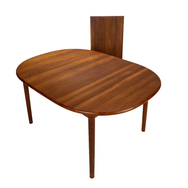 Solid teak Danish modern dining table with a clean oval top and integrated extension leaf. The table has been freshly...