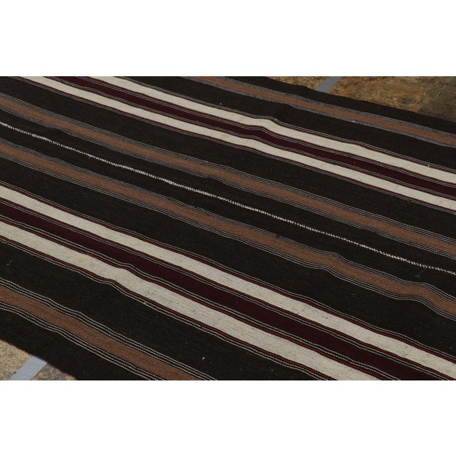 Handwoven in a wool flatweave originating from Turkey circa 1950-1960, this 5x7 vintage Kilim rug connotes a mid-century...