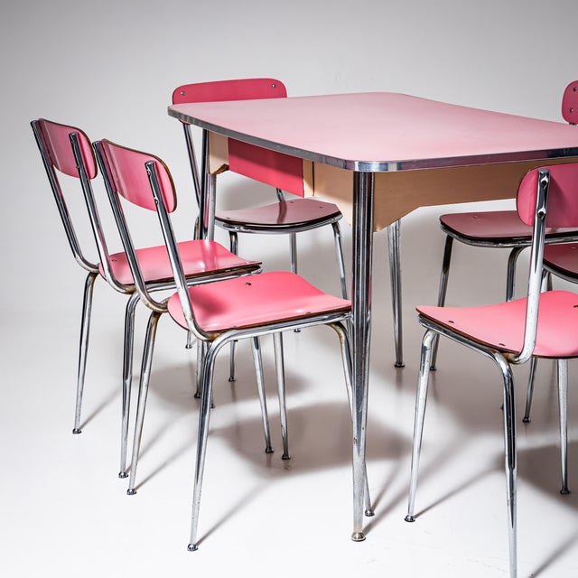 Dining set consisting of a table and six chairs in chrome-plated metal with a pink Formica surface. Showing age-related...