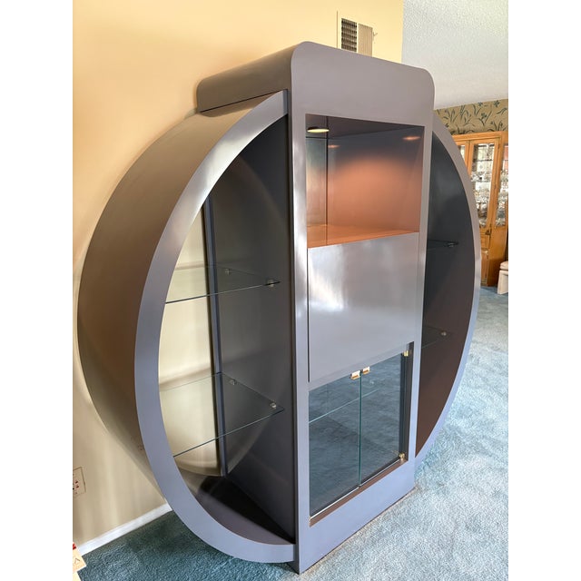 Sensational customer grey laminate and glass wall unit having sculptural shape, brass hardware on doors, center section...
