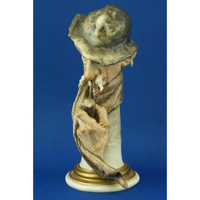 Item description: Polychrome hard-paste porcelain sculpture depicting the bust of an elderly man with a pipe, scarf, and...