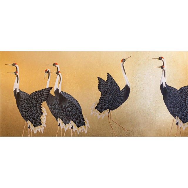 A sophisticated hand painted scenic wallpaper mural featuring graceful cranes set against a rich metallic gold background....