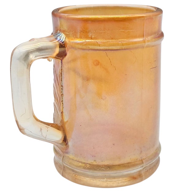 This pressed-glass mug represents early twentieth-century American carnival glass production attributed to Dugan Glass...