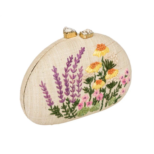Dome clutch in natural raffia embroidered with a wild garden. Ivory stone clasp closure. Lined with slip pocket and drop...