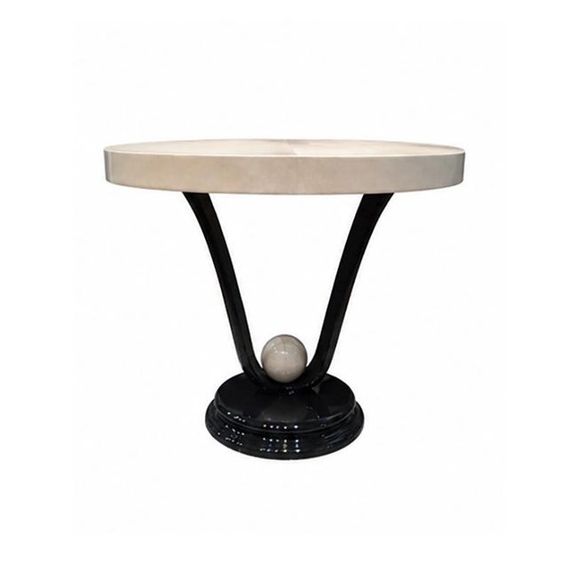 A round table made of black lacquered wood, supported by three curved black lacquered legs and featuring a white marble...