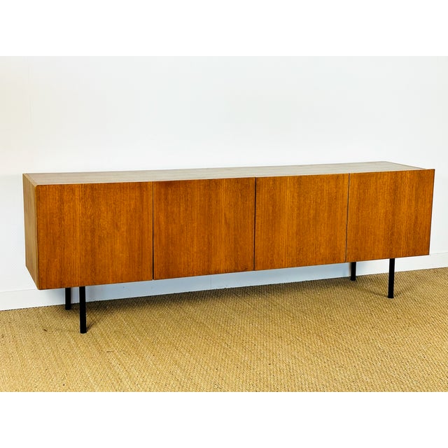 A low teak sideboard with a scandinavian modernist design from the 1960s. featuring a fine, even grain that highlights the...