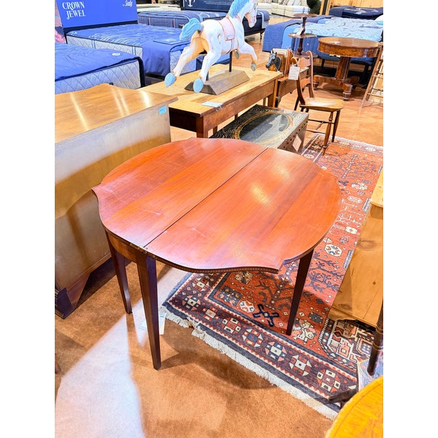 This is a beautifully crafted mahogany swing-leg gateleg table with a warm, rich wood tone and a softly contoured oval...