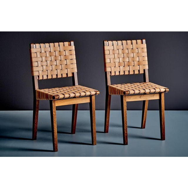 A rare pair of French dining chairs from the 1950s. The solid wooden frames show a clear architectural structure, with...