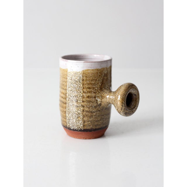Vintage handmade studio pottery mug showcasing an organic modern form with a sculptural side handle and richly textured...