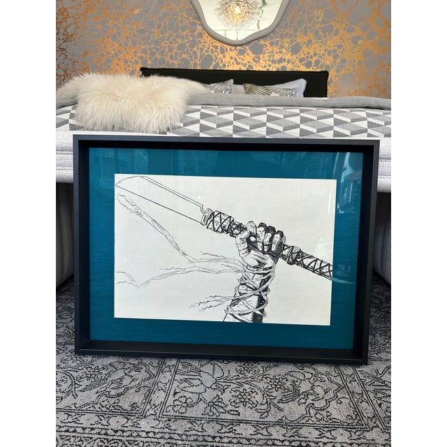 Ink drawing of a hand holding a sword inspired by the comic Vinland Saga. Glass framed with blue silk mat. 23.75x17.75"...