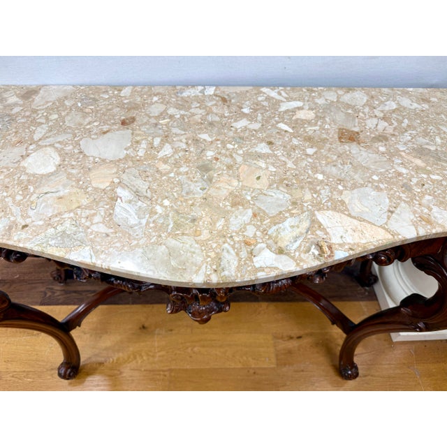 An exquisite Italianate carved walnut console table, richly detailed with dramatic Rococo-inspired ornament and a warm,...