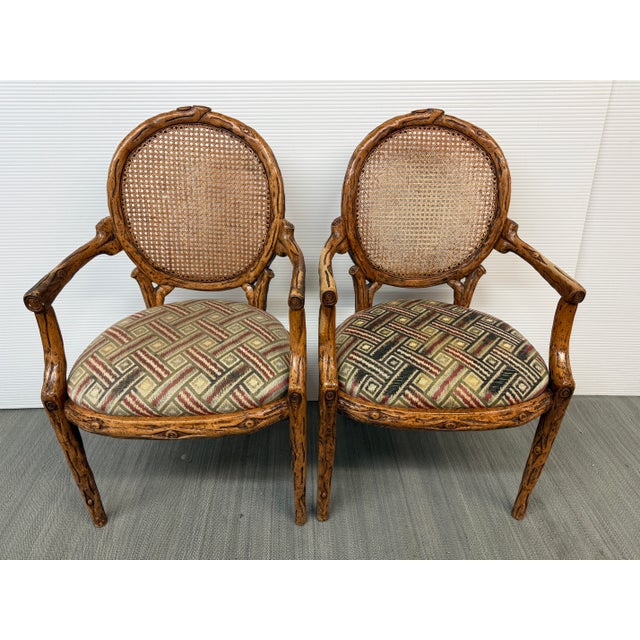 Design Plus Gallery presents a Pair of Caned Back Arm Chairs. The likely vintage chairs have a distressed and notched wood...