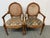 Design Plus Gallery presents a Pair of Caned Back Arm Chairs. The likely vintage chairs have a distressed and notched wood...