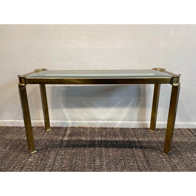 A console table by Mastercraft Furniture with a brass frame and curved corners typically complements side tables from the...