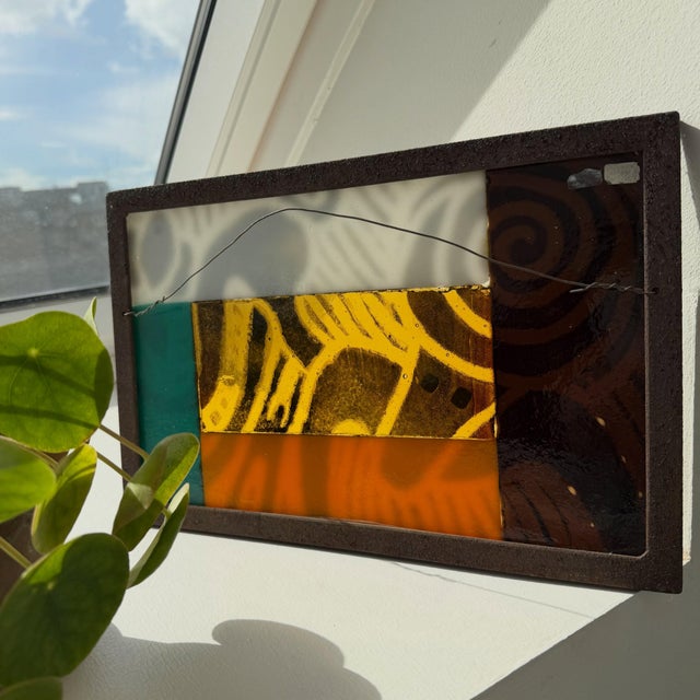 Decorative glass relief from the 1970s, mounted in an iron frame. The coloured glass and varied surfaces catch and...