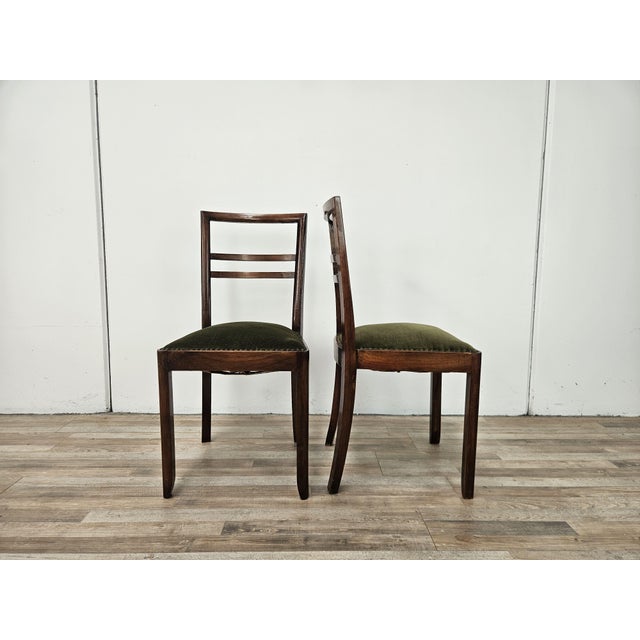 A pair of walnut chairs with a forest green fabric upholstered seat, decorated with studs along the entire edge. The...