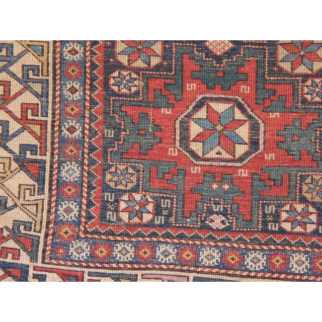 This beautiful antique Caucasian Lesghi rug features a striking deep blue field accented by rich green, soft ivory, and...
