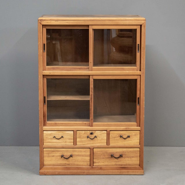 Early 1920's Japanese cedar display cabinet with sliding glass doors and five drawers. Very clean and lightweight with...