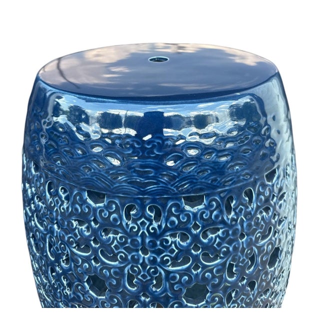 The Clark Garden Stool is a ceramic garden stool with a barrel form and an ornate scrollwork pierced pattern in a high-...