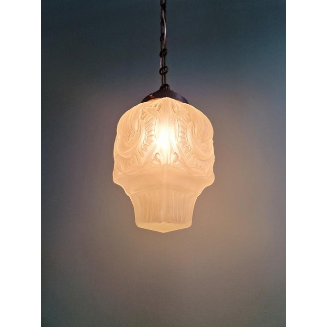 Art Deco pendant light with a frosted molded pressed glass globe and a copper-plated metal frame, 1920s-30s. This pendant...