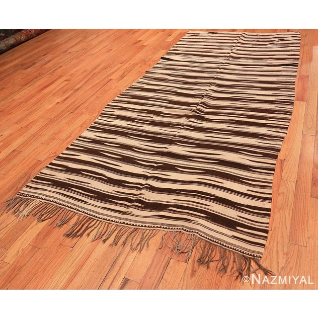 This chic vintage Moroccan Kilim features an abstract pattern of expressive stripes and geometric decorations rendered in...