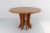 Beautiful round wooden dining table with an elegant central pedestal made up of shaped and rounded slats, positioned in a...